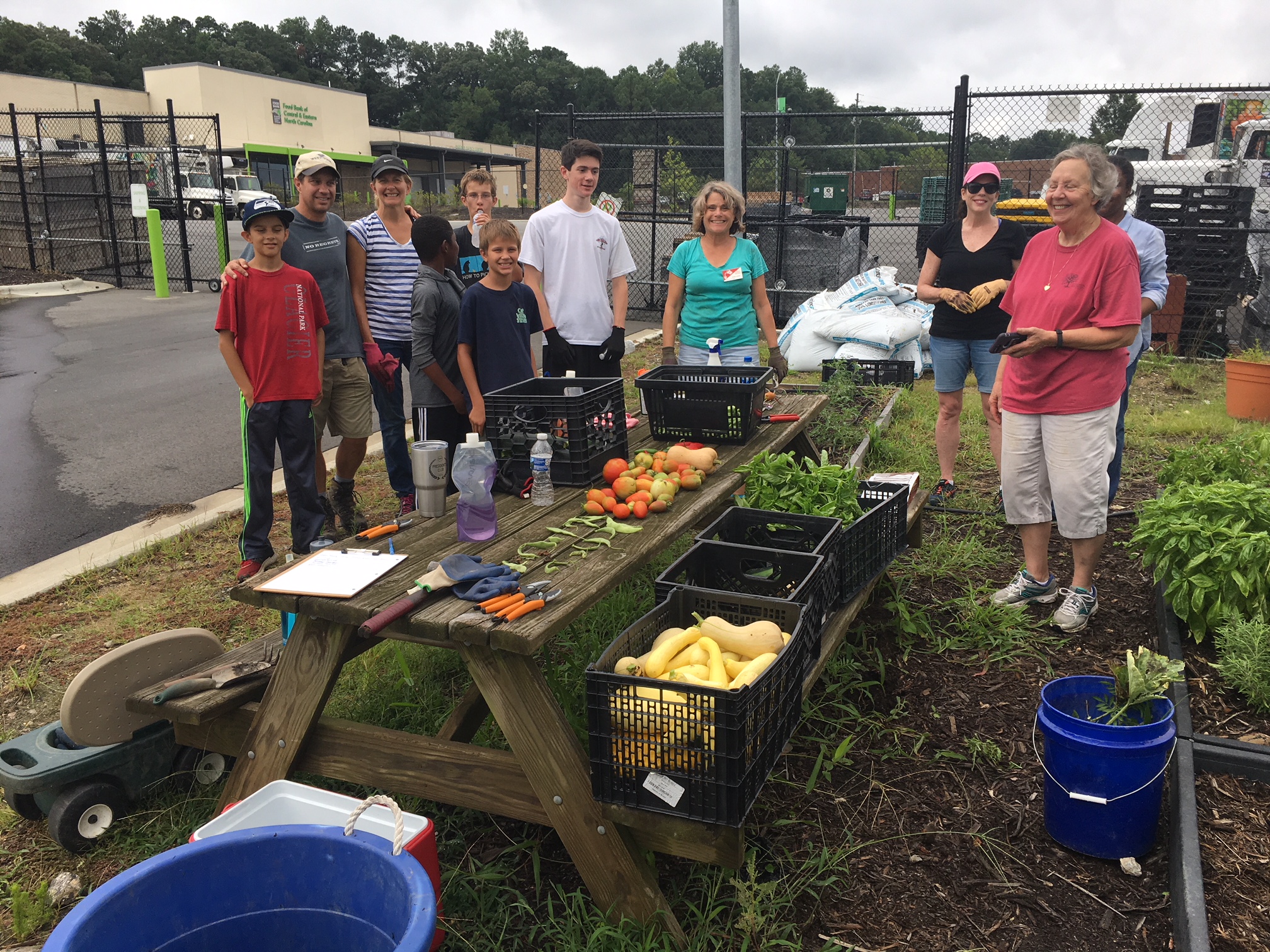 A group of volunteers stand with Extension Master Gardener Volunteers at the food bank of central and eastern north carolina's community and demonstration garden