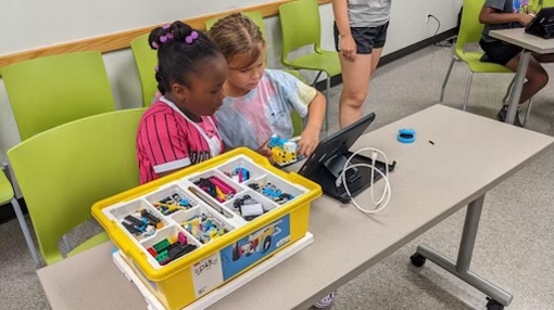 Two young campers use legos and a tablet for a STEM activity
