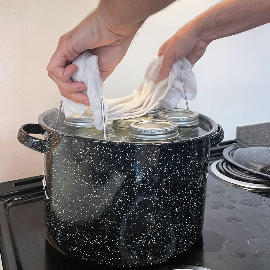 Jars being processed in a boiling-water canner, with a visible water level and lid on the canner